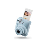 Fujifilm Instax Mini 12 Instant Film Camera — Fujifilm Instax Mini 12 instant camera, front three-quarter view showing the round lens barrel and selfie mirror